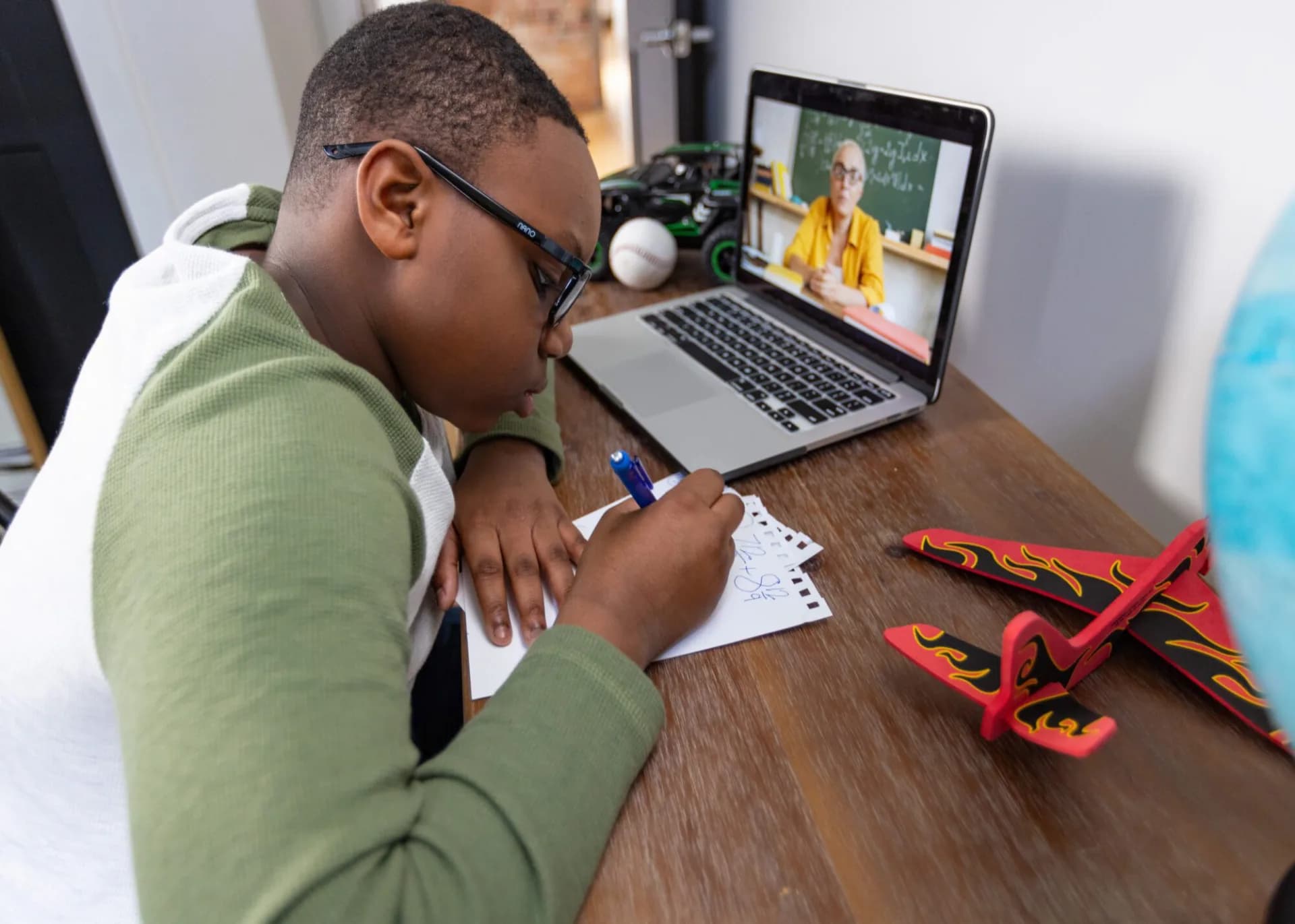 Middle school student taking notes during a live online lesson on a laptop
